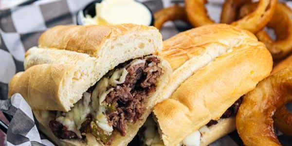Greco's sandwiches menu featuring the Philly cheesesteak served with fried onion rings